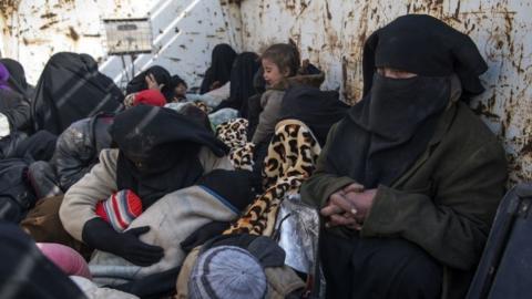 Women and children who fled the Islamic State (IS) group's embattled holdout of Baghouz on sit waiting in the back of a truck in the eastern Syrian province of Deir Ezzor.