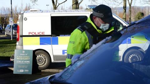 A police officer speaks to the driver of a car