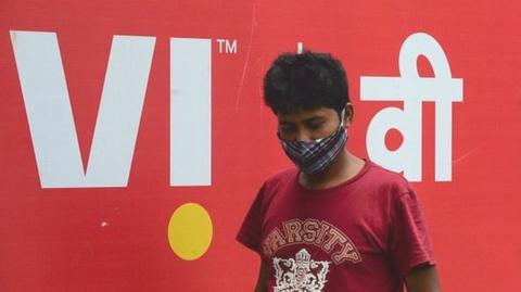 A pedestrian walks past the logo of mobile carrier Vodafone Idea in Mumbai on September 16, 2021.