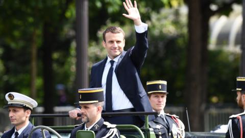 French President Emmanuel Macron (C) waves as he parades in a car on the Champs Elysees avenue after his formal inauguration ceremony as French President on 14 May 2017 in Paris.