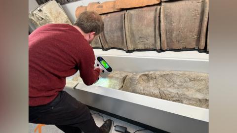An archaeologists uses a 3D scanner to study a gypsum burial casing