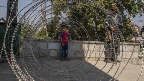 A Kashmir child look towards his parents after he was helped by Indian paramilitary trooper to cross the concertina razor wire laid by Indian government forces during curfew like restrictions, on September 10, 2019 in Srinagar