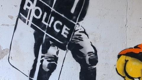 Section of a graffiti artwork showing a cartoon character baring his backside at a police officer