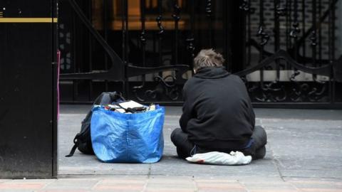 A homeless person sits in a Glasgow city centre street on March 27, 2020