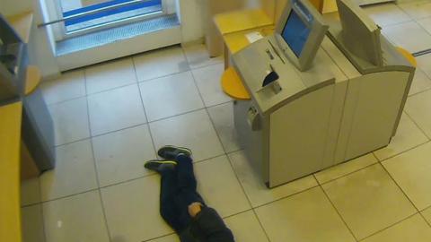 Bank CCTV shows pensioner lying next to cash machines (Essen police photo)