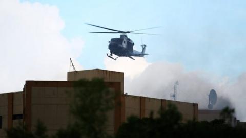 A Salvadoran army helicopter flies over the ministry of treasury building during a blaze in San Salvador, El Salvador, July 7, 2017.