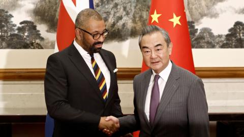 British Foreign Secretary James Cleverly and Chinese Foreign Minister Wang Yi shake hands before a meeting at the Diaoyutai State Guesthouse in Beijing, China