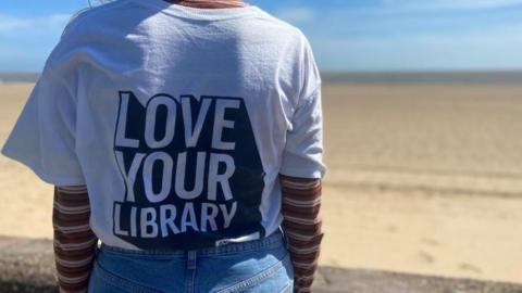 The back of a female wearing a T-shirt that reads "Love Your Library