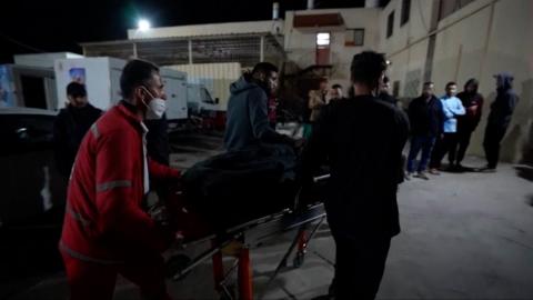 A person being wheeled into hospital on a gurney by hospital workers