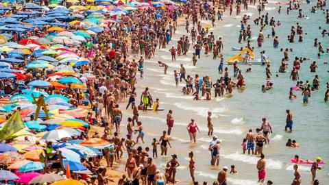 People sunbathe at Levante Beach in Benidorm, Spain