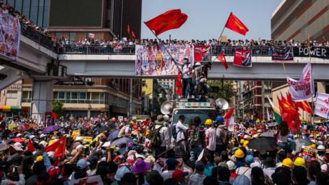 Protesters wave red NLD flags at Sule Square on February 22, 2021 in downtown Yangon, Myanmar.