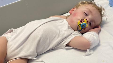 Archie Stevens asleep on a hospital bed