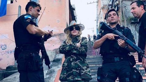 Madonna poses with military police wielding guns in a Rio de Janeiro slum.
