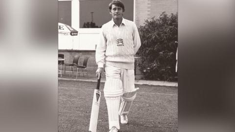 Robin Hobbs wearing a cricket uniform and holding a cricket bat