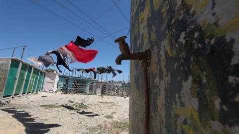 Clothing hangs above a communal tap in Khayelitsha township, near Cape Town, South Africa, 12 December 2017