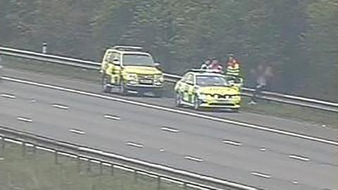 Two traffic vehicles by the side of the motorway with officers talking to teenagers