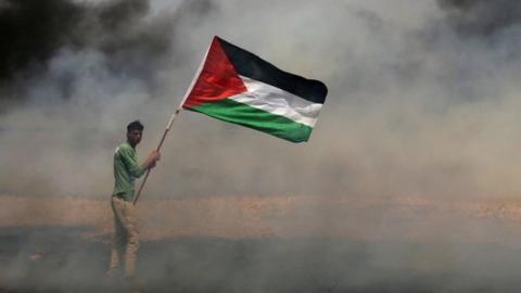 A demonstrator holds a Palestinian flag during clashes in the Gaza Strip in 2018