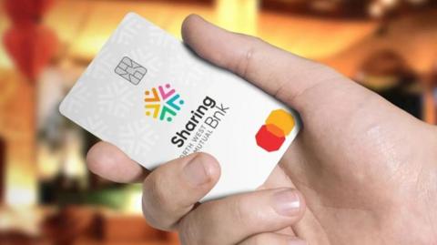 A close up of a hand holding a white bank card