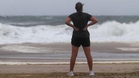 A woman watches the waves from Hurricane Erin in New Jersey