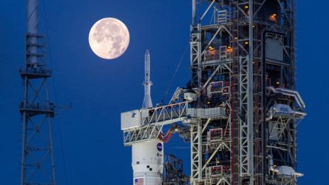 Artemis II on the launchpad. The moon is in the distance