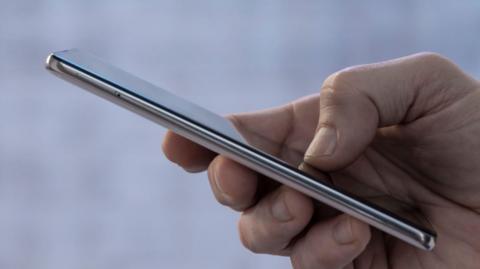 Close-up of a male hand holding a slim grey mobile phone