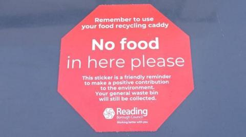 A Reading Borough Council sticker on a black bin saying "No food in here please".