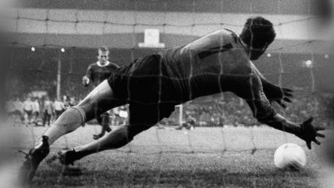Archive photo of penalty. Goalkeeper diving right as a white ball approaches on the ground.