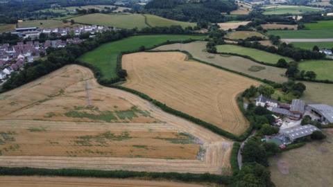 Fields to the west of Newton Abbot with buildings to the right of the picture and houses to the left.