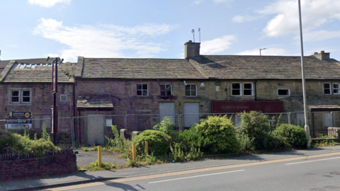 Stone two storey building with boarded up doors and windows