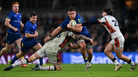 Scott Penny is tackled by Glen Young, left, and Charlie Shiel of Edinburgh during the United Rugby Championship match between Leinster and Edinburgh