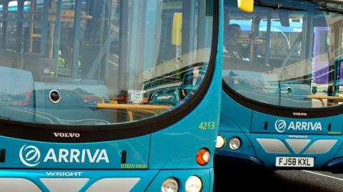 A close-up of two parked Arriva buses, side-by-side. They are blue Volvo models, with large front windows and white Arriva logos above the bumpers.