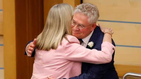 Alison Johnstone embraces Kenneth Gibson before vacating presiding officer's chair