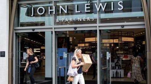 Two women leaving a John Lewis shop on a sunny day