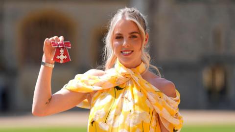 Keely Hodgkinson holds up her MBE at Windsor Castle
