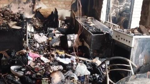 A badly fire-damaged kitchen with charred appliances and rubble.