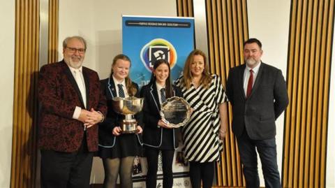 Sgioba Sgoil Sir E Scott còmhla ris na britheamhan às dèidh dhaibh Deasbad Nàiseanta nan Àrd-sgoiltean a bhuannachadh ann an 2025