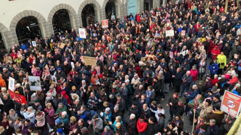 A large gathering of people with protest signs and placards against GST. 