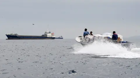 Vessels and a boat at the Strait of Hormuz, off the coast of Oman’s Musandam province