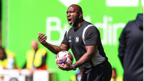 Port Vale boss Darren Moore gets ready to throw on the match ball from the touchline during a game 