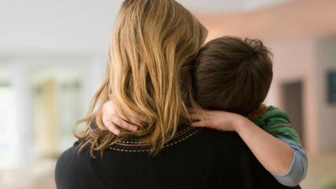 Young child with head buried in mother's shoulder