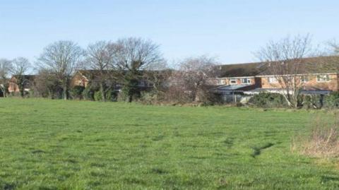 The Folly field, with a row of trees in front of local houses