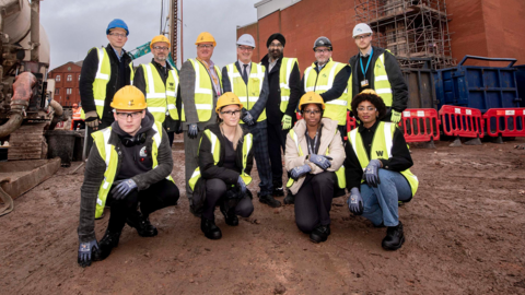 A group of people in hi-vis vests and hard hats on the building site for the City Learning Quarter city centre development