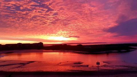 Pink sky and clouds over water 