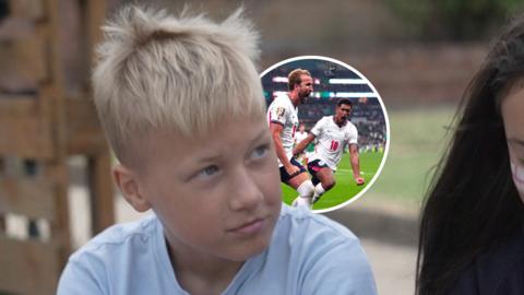 A young child sits outdoors while a circular graphic over the image shows England football players celebrating.
