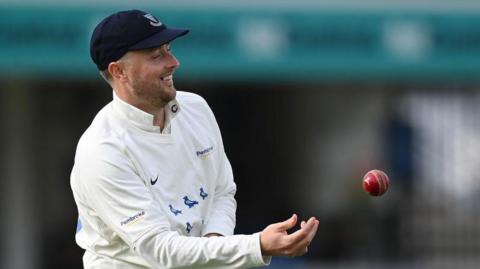 Ollie Robinson smiles as he tosses the ball to a team-mate 