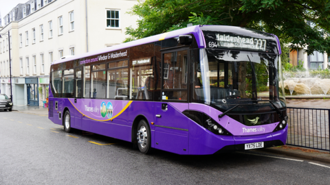 A purple, single decker bus parked on the side of a road. It says Maidenhead - 227 - on a screen above its windscreen.