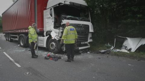 Dau swyddog heddlu yn edrych ar y niwed i un o'r ddwy lorri oedd yn y gwrthdrawiad