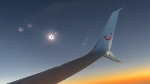 An eclipse next to a plane wing