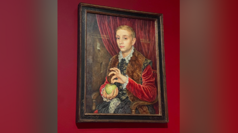 Boy with Apple portrait against a red background.
