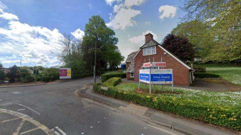 The entrance to Torbay Hospital which is marked with a blue rectangular sign that reads: "Torbay Hospital." 